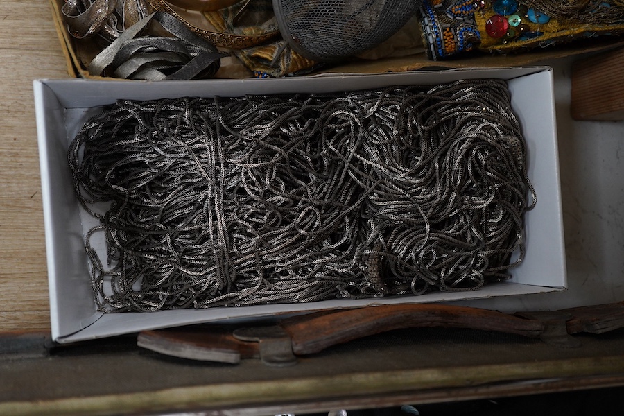 Two trunks containing a collection of children’s fancy dress from early 20th century, including an unusual child’s ‘pearly king’ suit, two earlier stockinette hats, a length of long silver metal fringing, ribboning etc.,